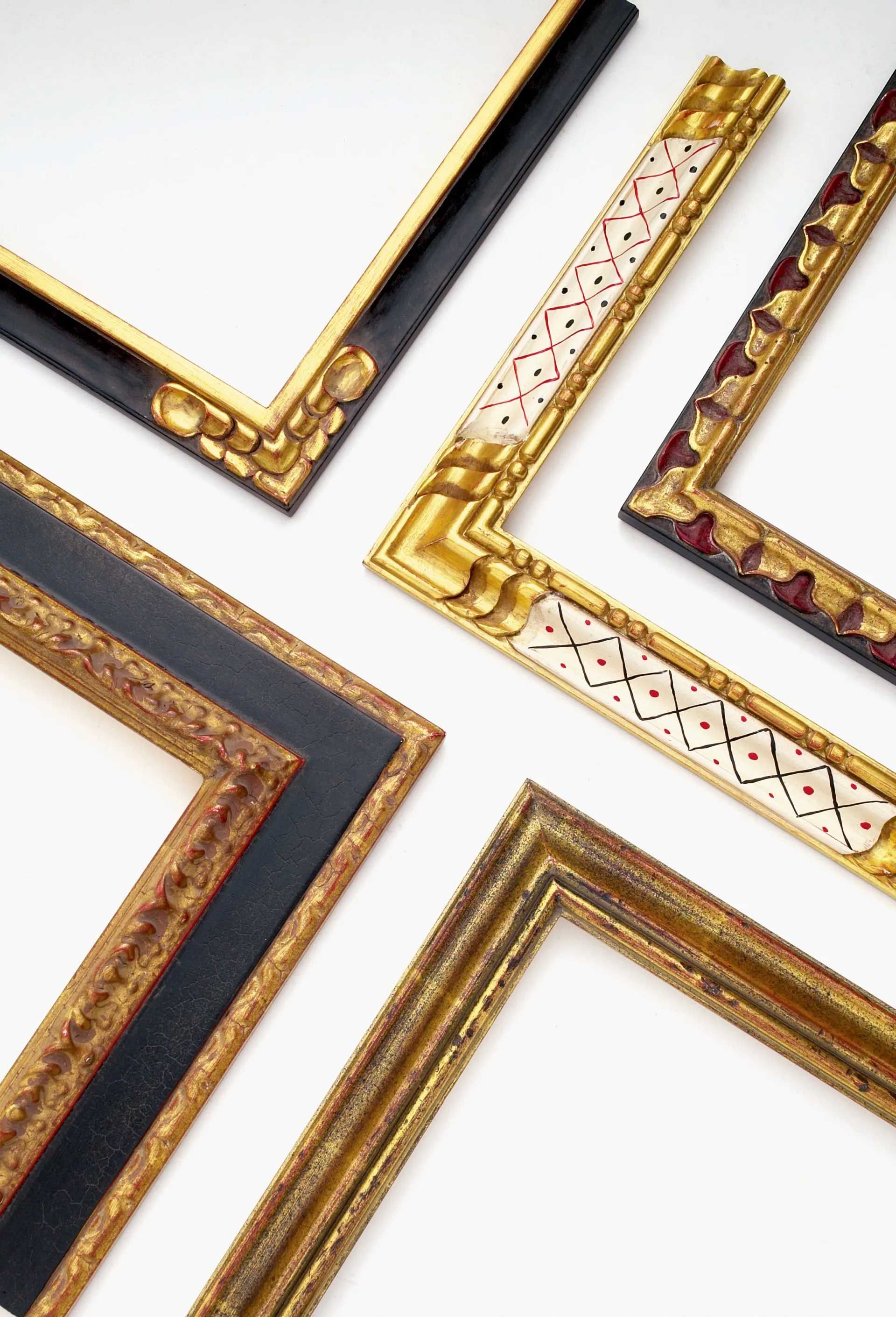 Four ornate picture frame corners in various styles of gold, black, and white on a white background.