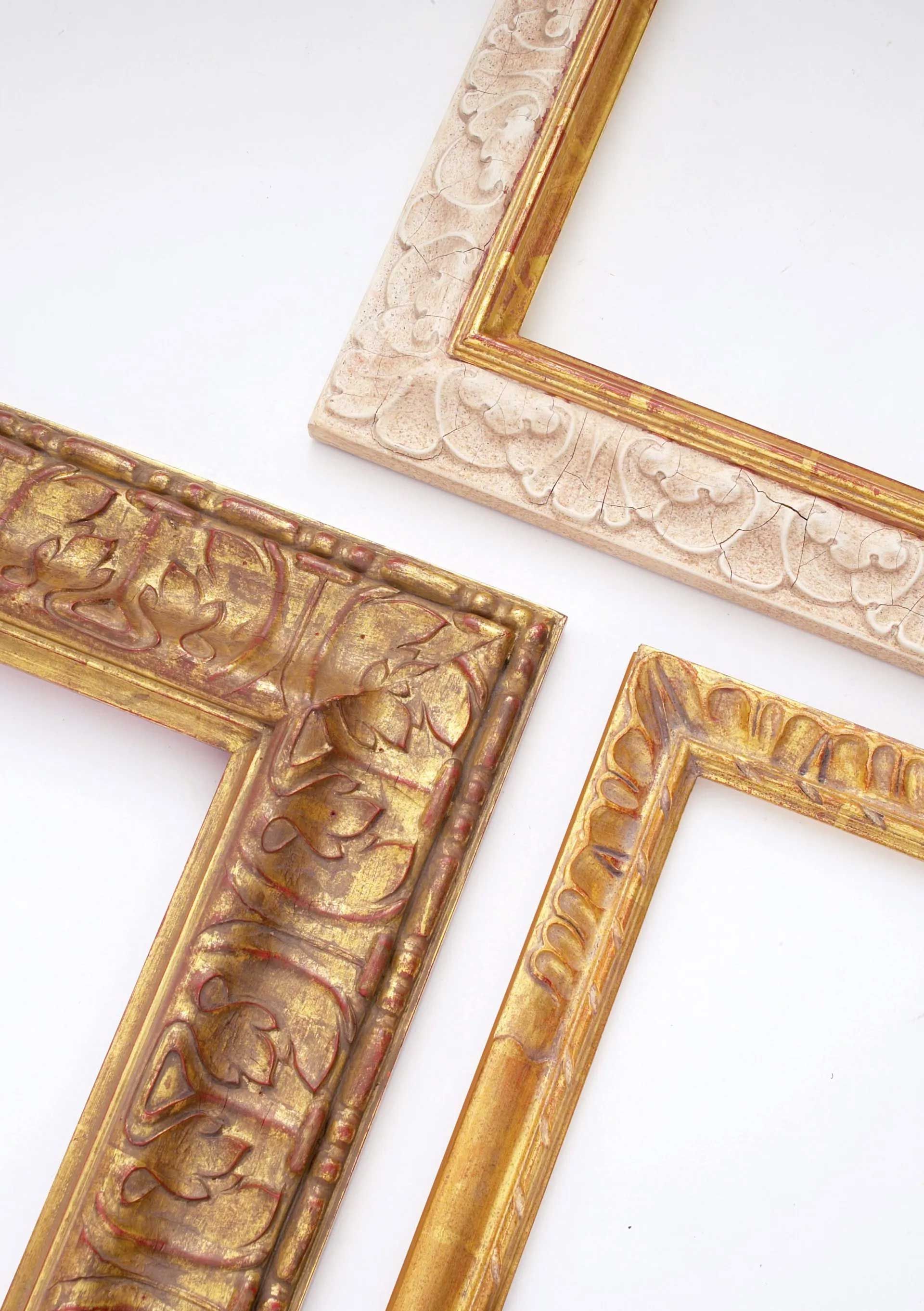 Three ornate, vintage-style picture frames in shades of gold and off-white arranged against a white background.