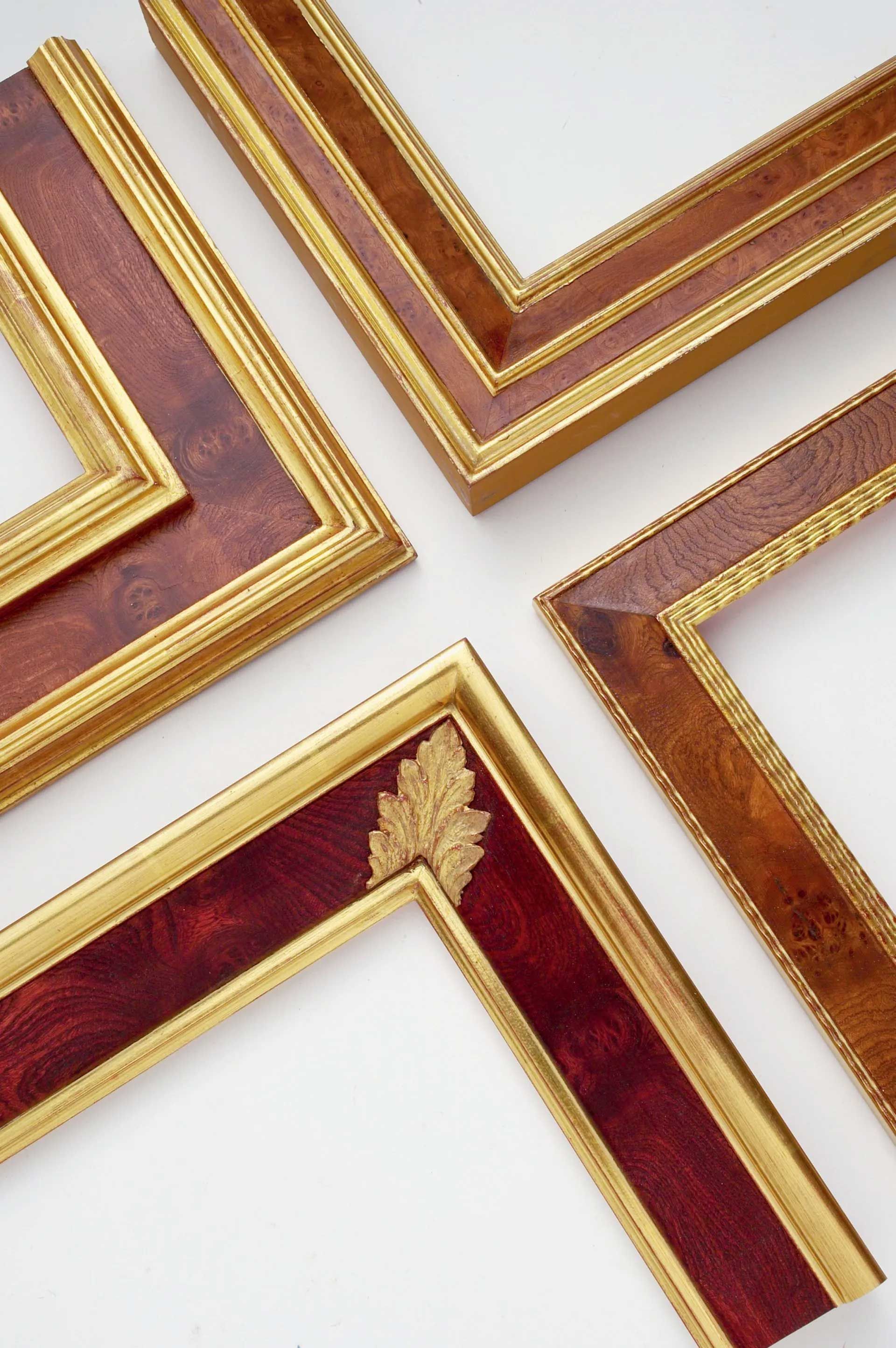Four corner samples of ornate, gold-trimmed wooden picture frames in various shades of reddish-brown and mahogany.