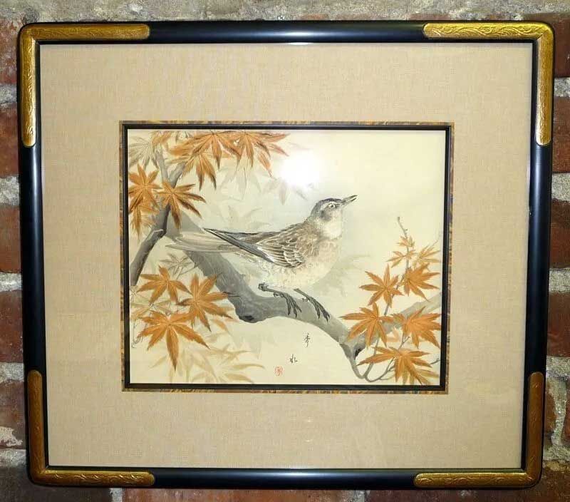 A framed Japanese-style painting of a bird perched on a branch surrounded by orange maple leaves.