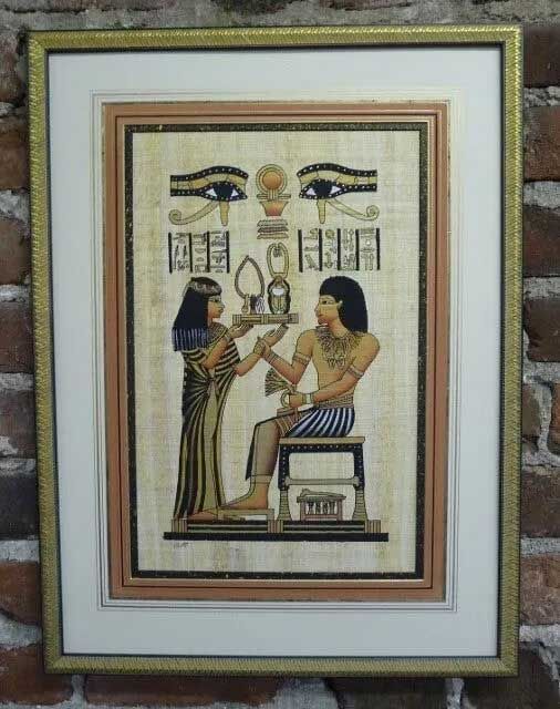 Framed Egyptian-style papyrus painting showing two figures with traditional clothing and symbols beneath two Eye of Horus.