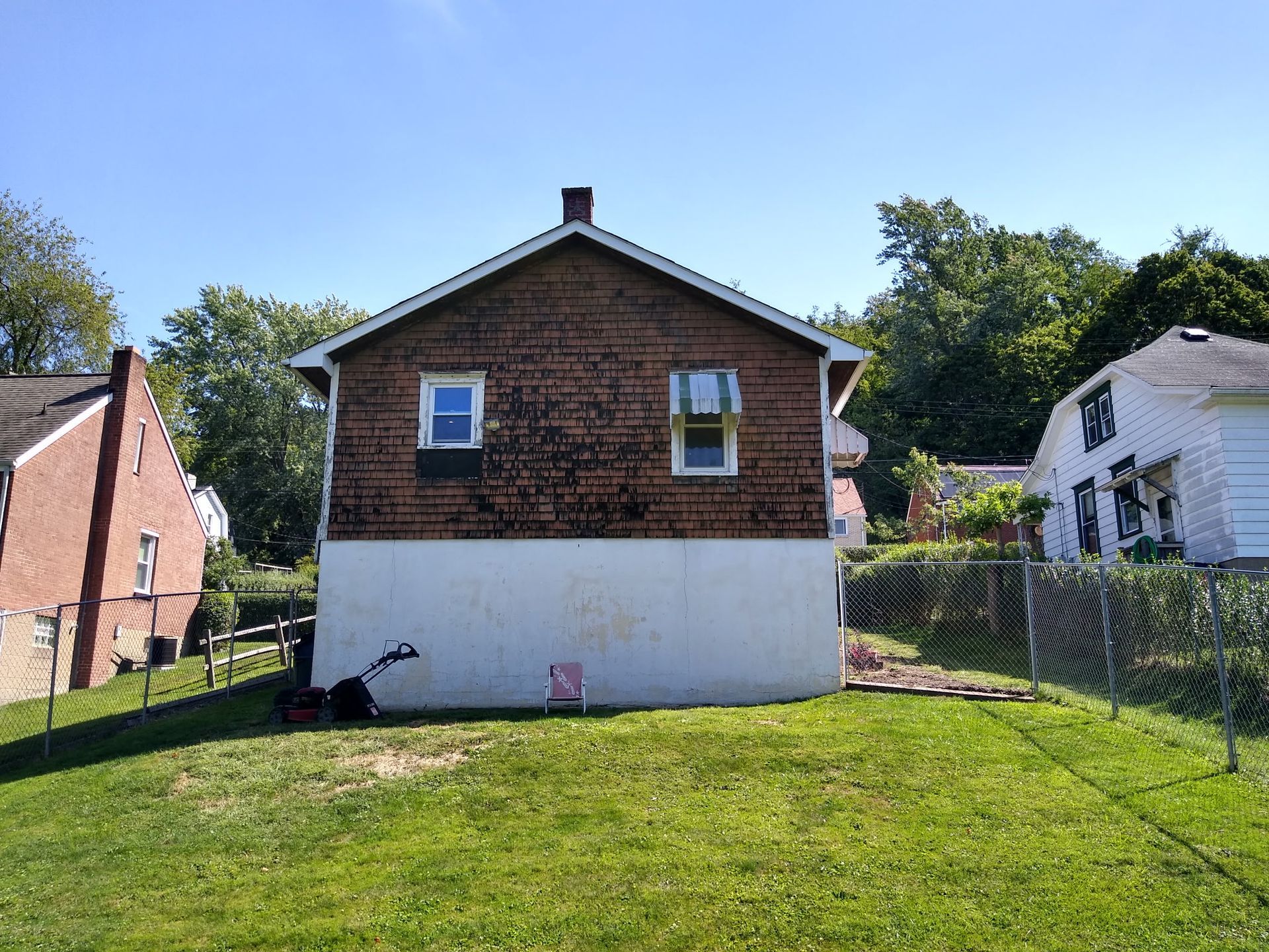 The back of a house with a lawn mower in front of it.