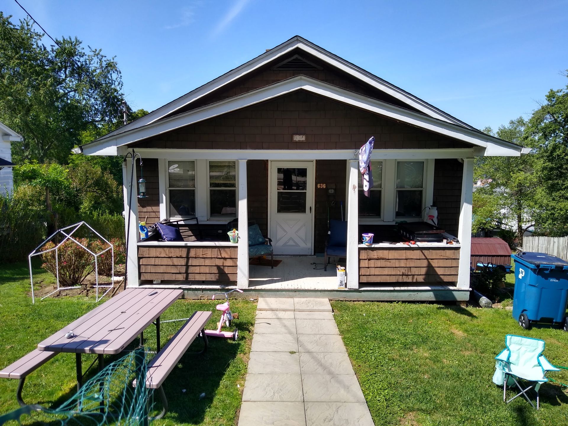 A small house with a porch and a picnic table in front of it.