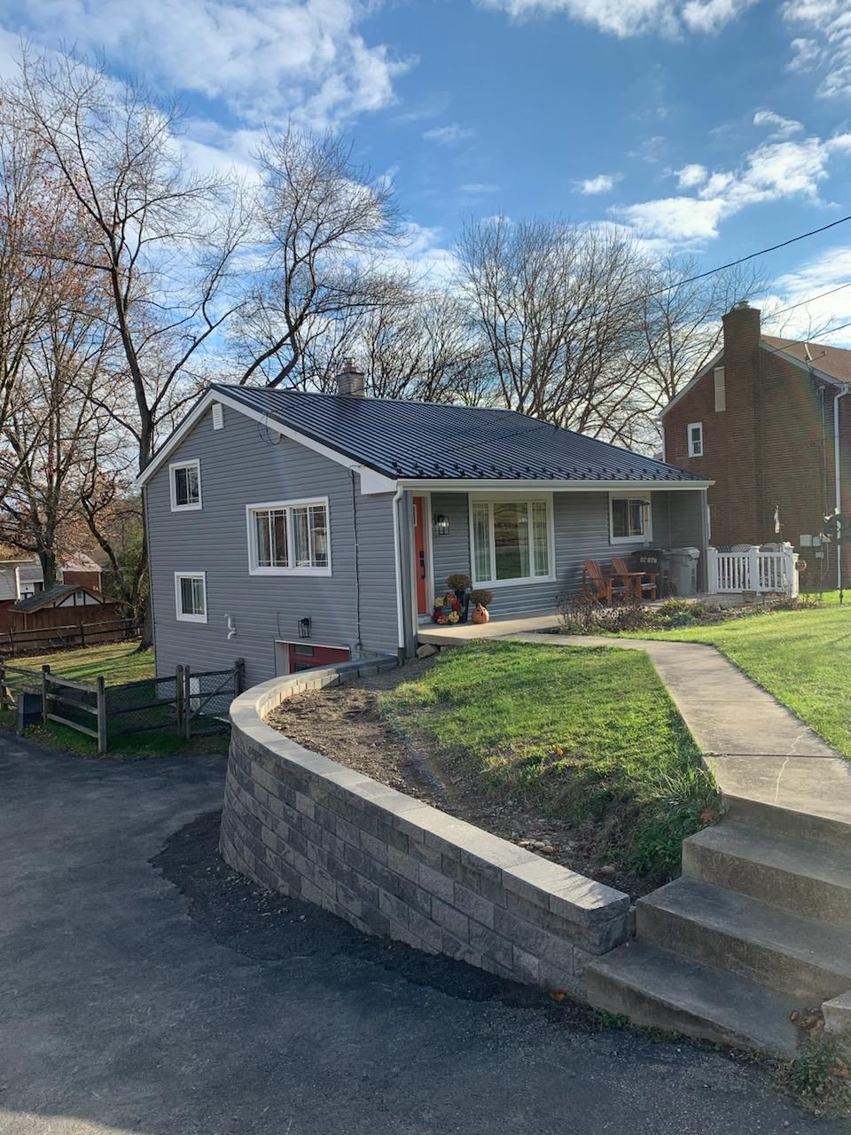 A small house with a brick wall and stairs in front of it.