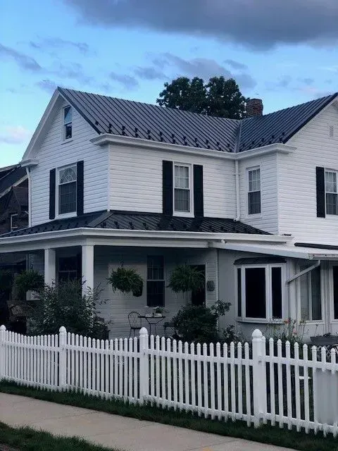 A white house with a white picket fence around it.