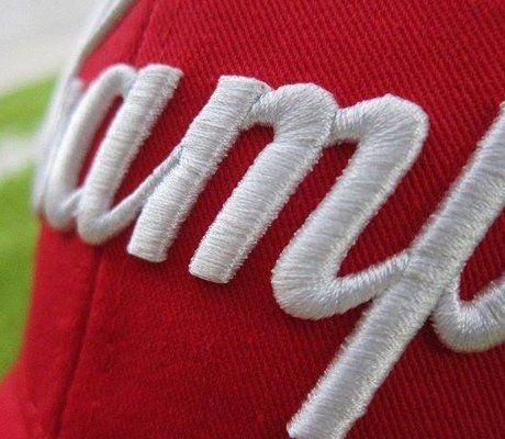 A close up of a red hat with the word camp embroidered on it