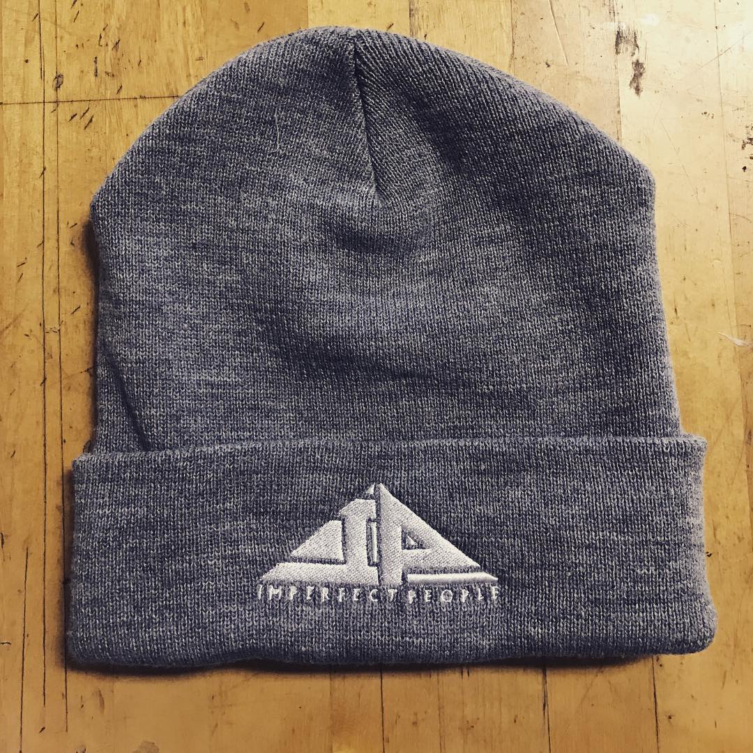 A grey beanie is sitting on a wooden table.