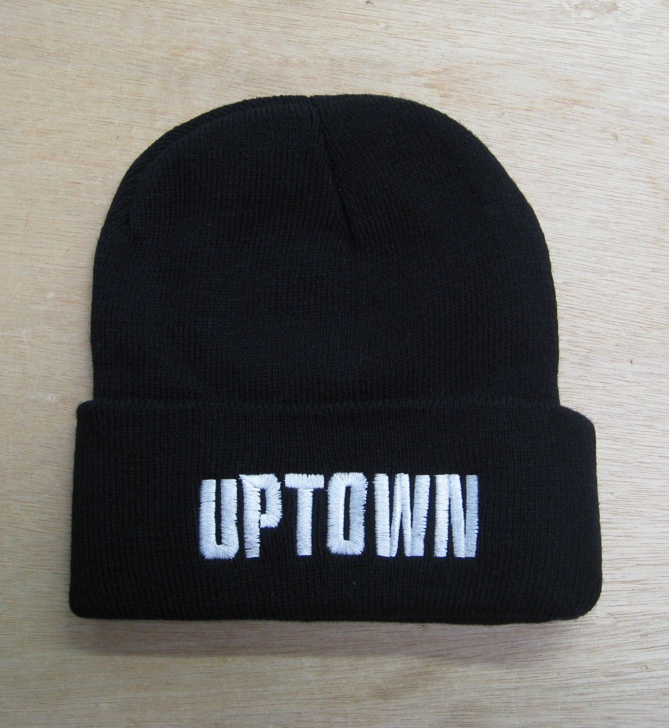 A black beanie with the word uptown embroidered on it