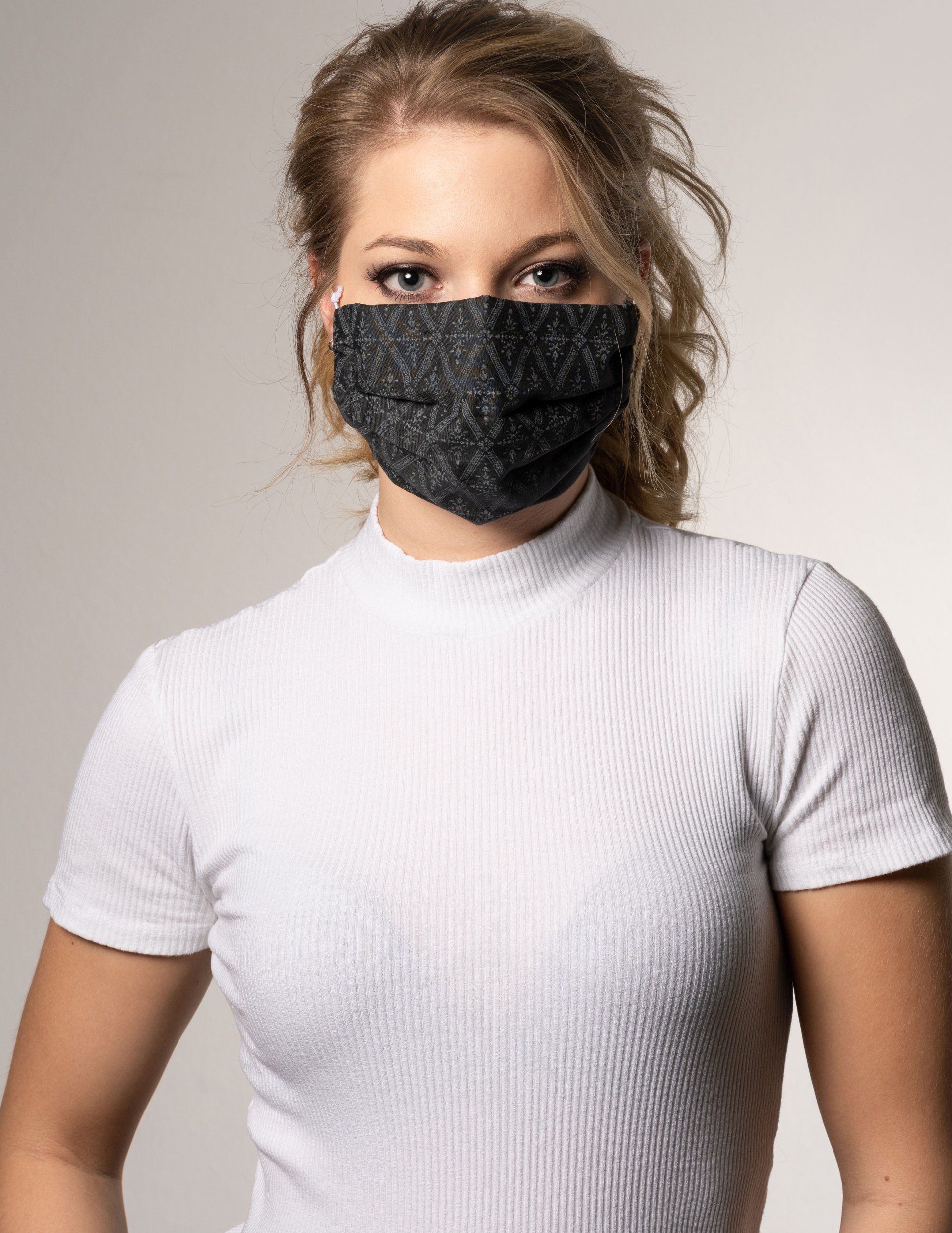 A woman wearing a white shirt and a black face mask