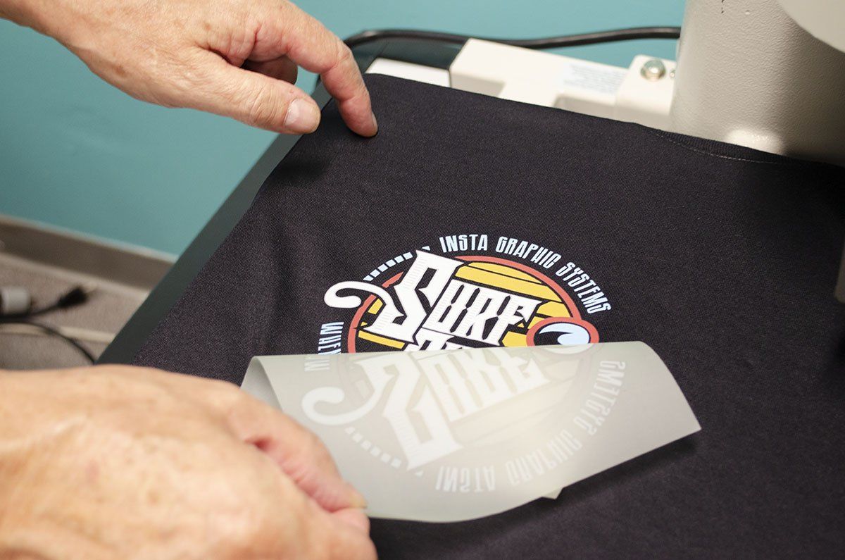 A person is putting a surf logo on a shirt