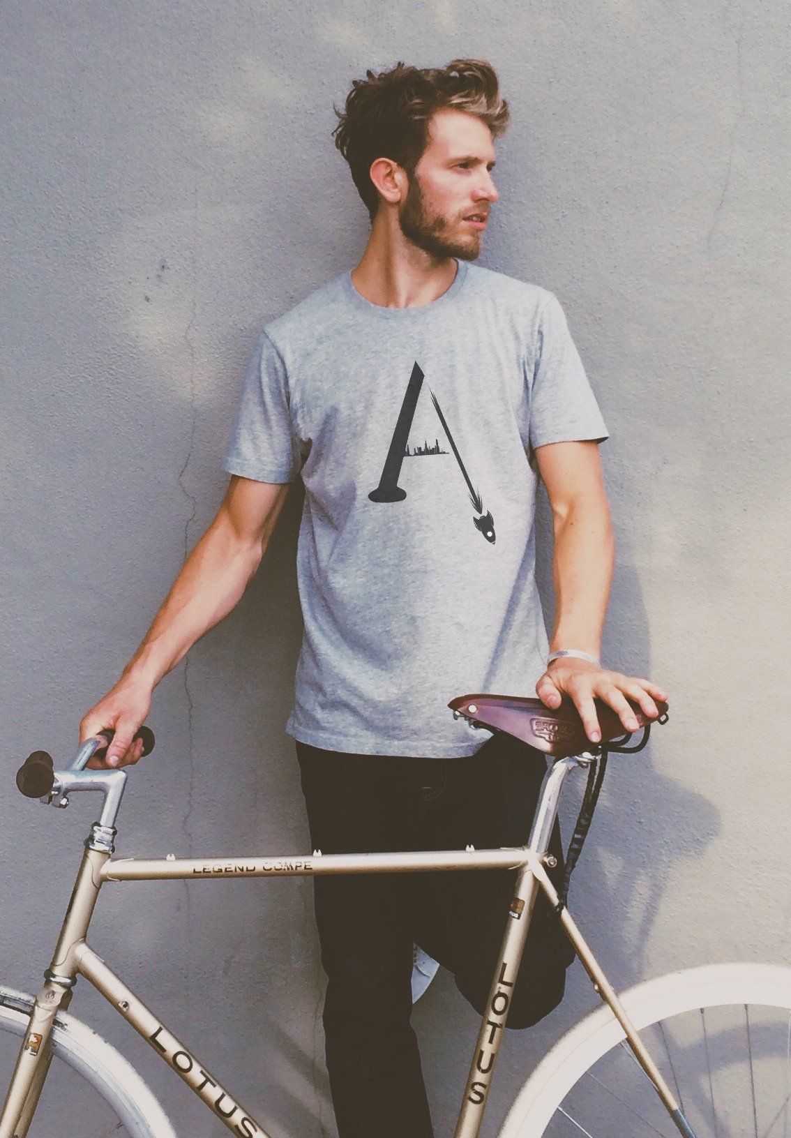 A man leaning against a wall with a bicycle in front of him