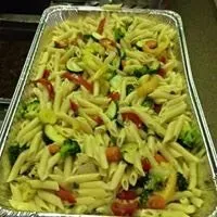 Penne pasta salad with vegetables in a foil tray.
