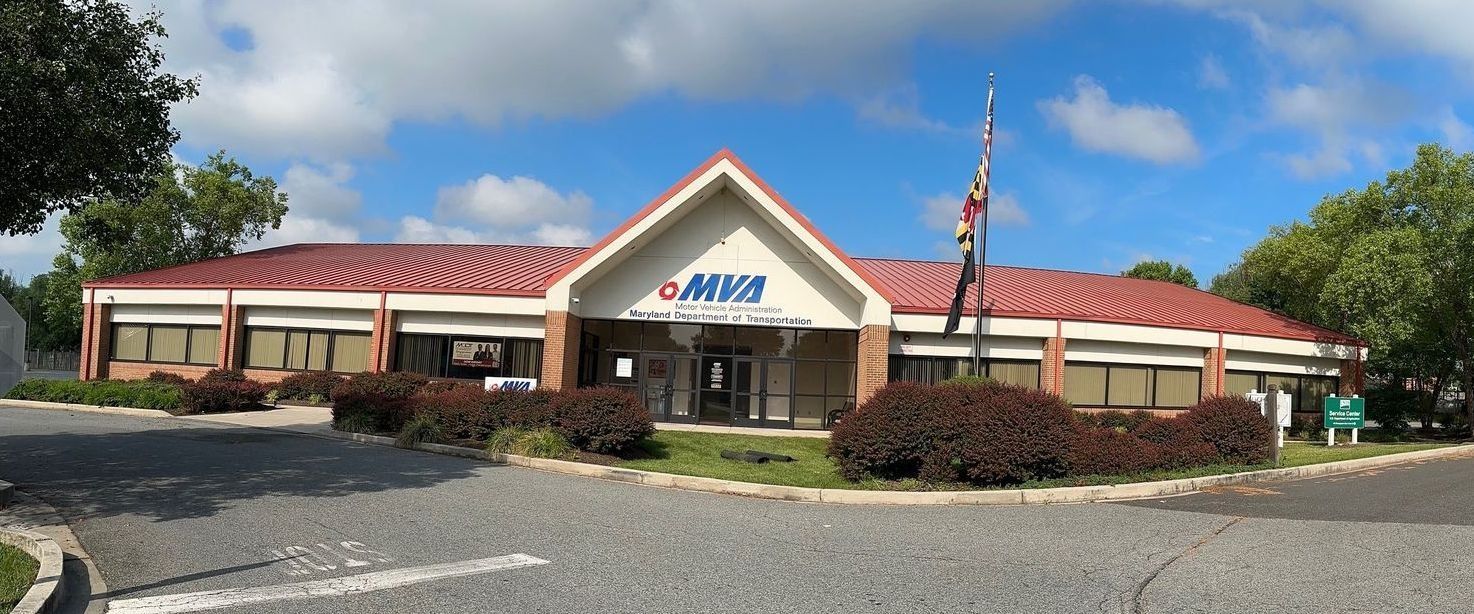A single-story brick building with a red roof, a flag, and a sign that reads 