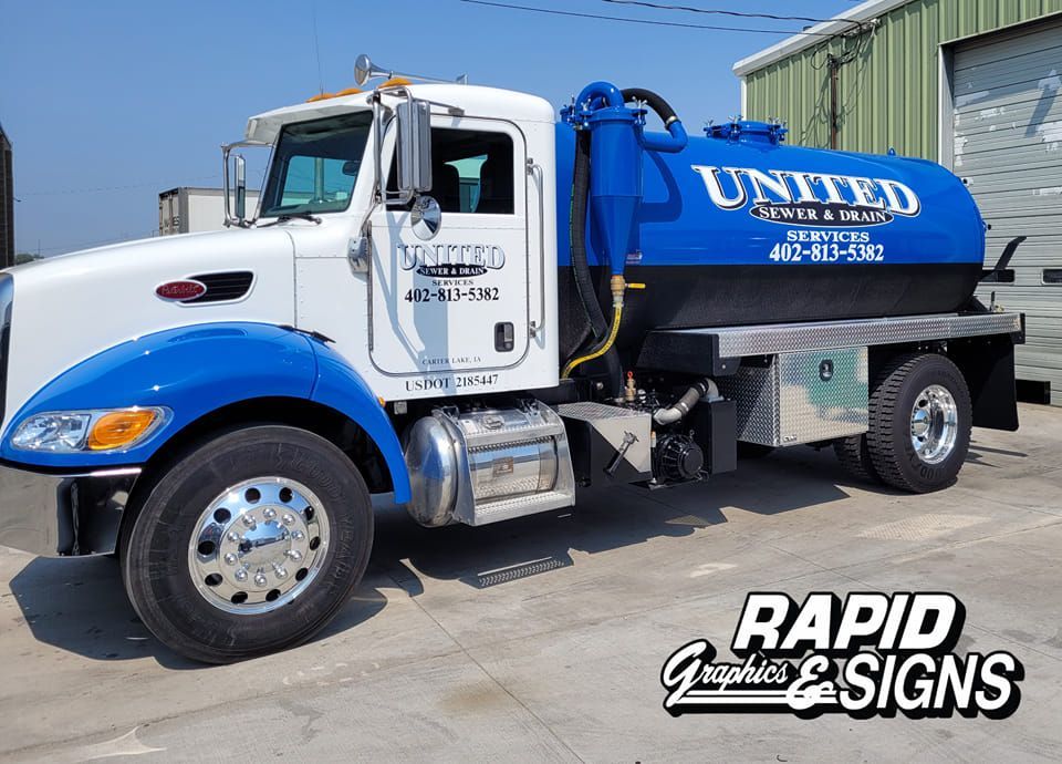 A blue and white united vacuum truck is parked in a parking lot.