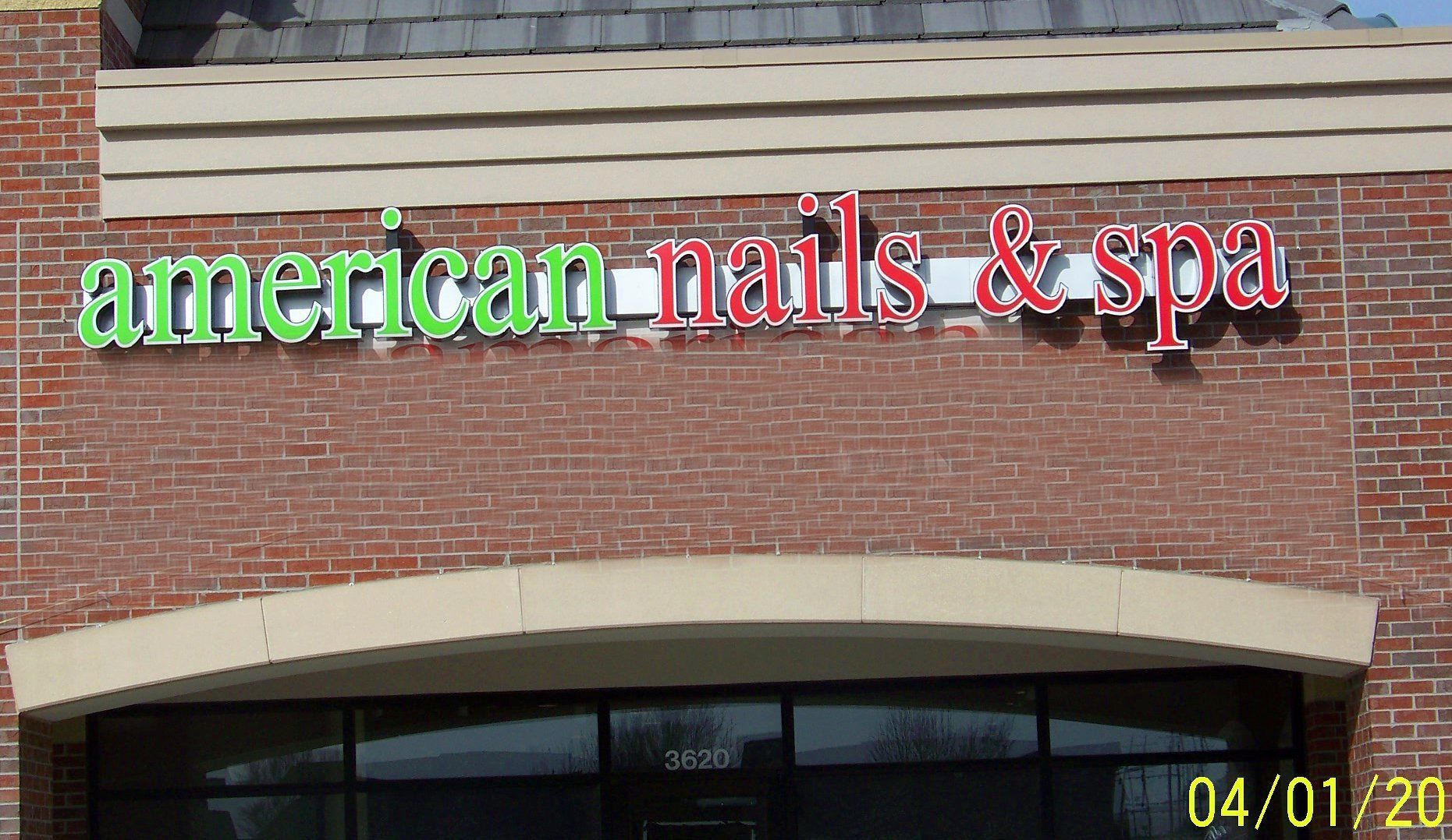 A brick building with a neon sign that says american nails & spa