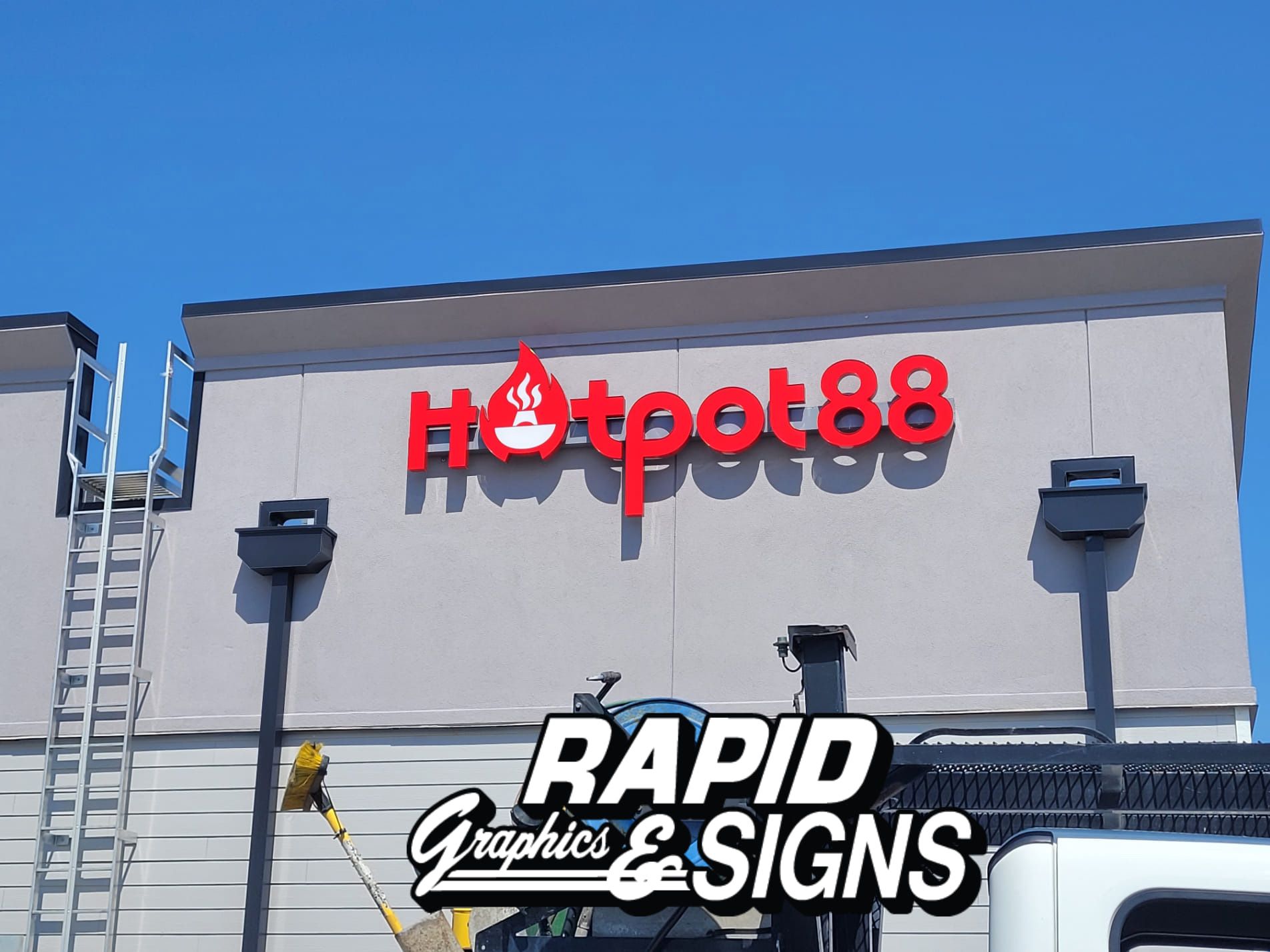 A sign for hotpot88 is being installed on the side of a building