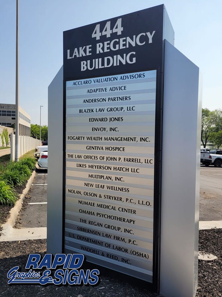 A sign for the 444 lake regency building is sitting in a parking lot.