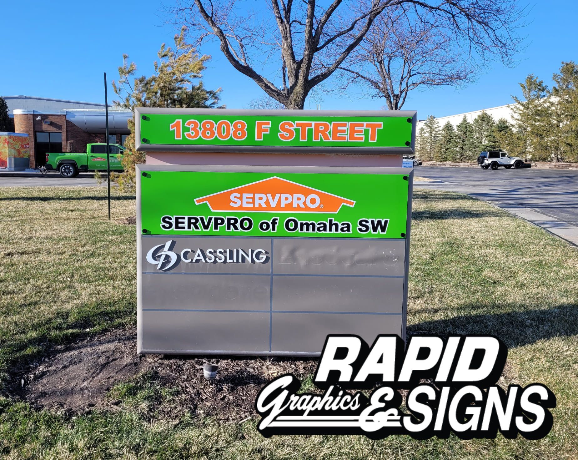 A sign for servpro is sitting in the grass in front of a building.