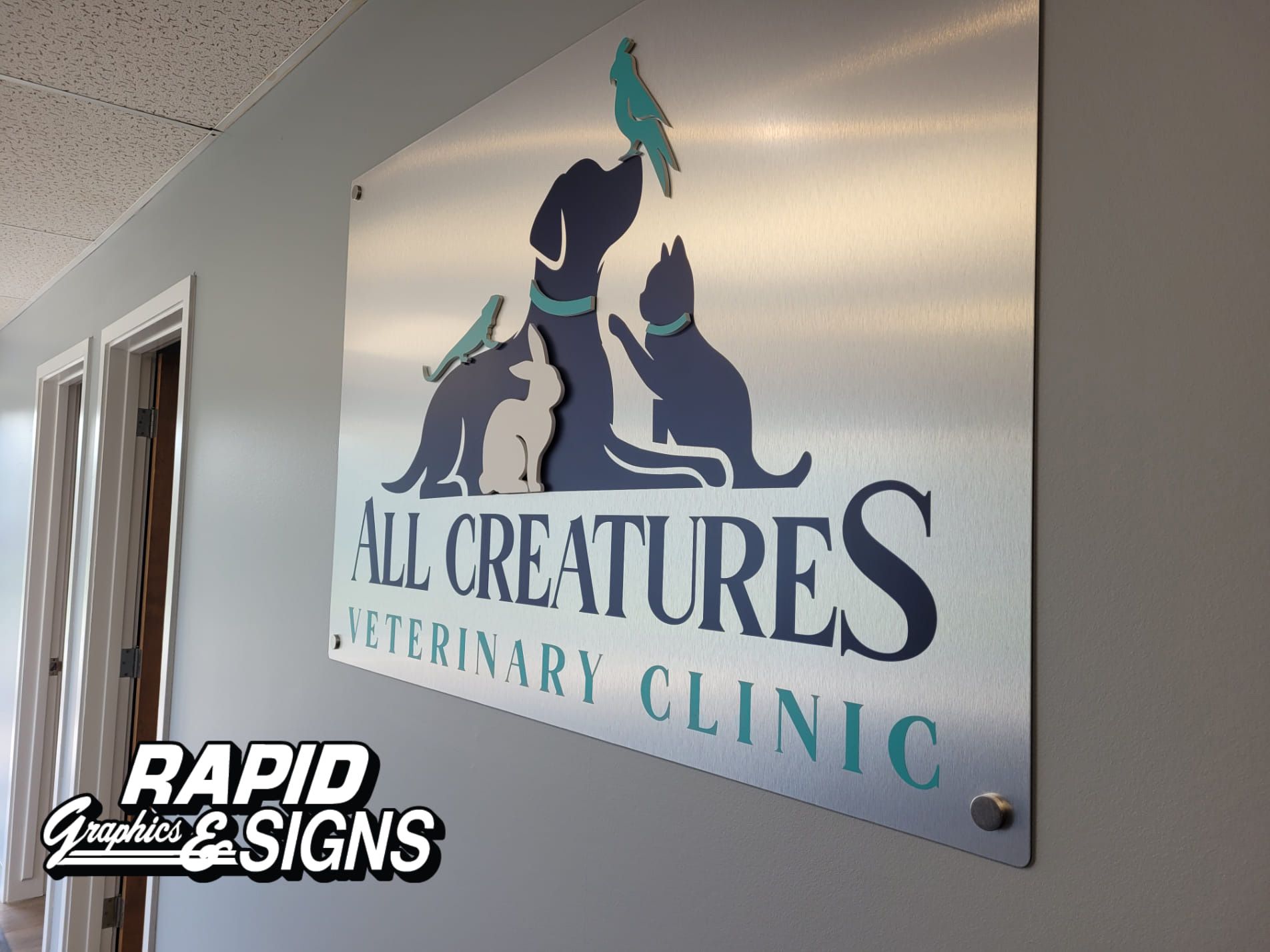 A sign for all creatures veterinary clinic hangs on a wall