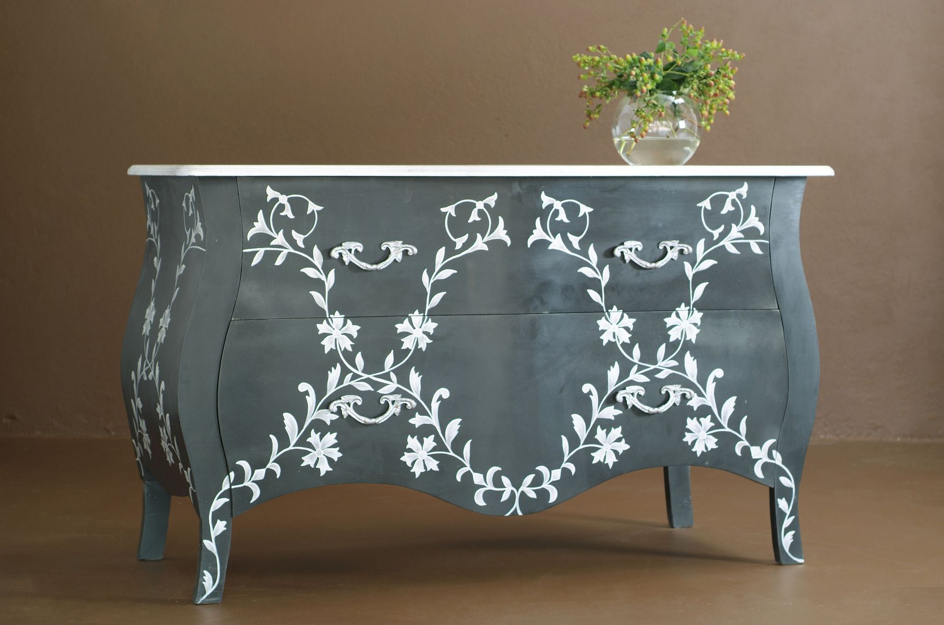 Gray painted chest of drawers with white floral design, white top, and a vase of flowers.