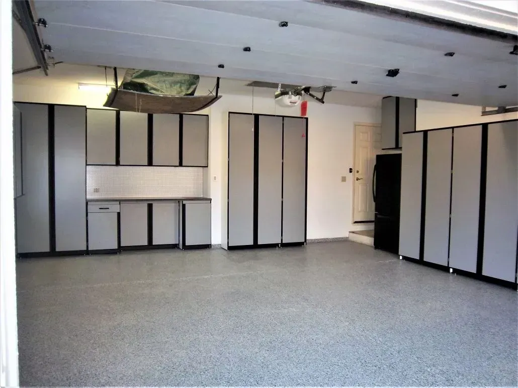 A clean garage with gray cabinets and flooring, organized storage space.