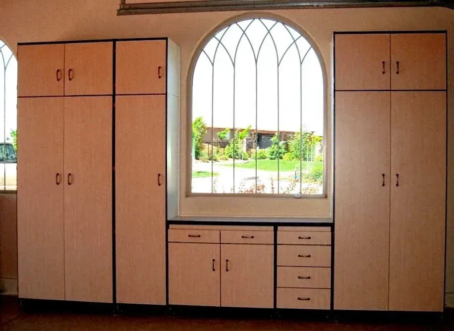 Cabinets of varying sizes flanking an arched window with an outdoor view.