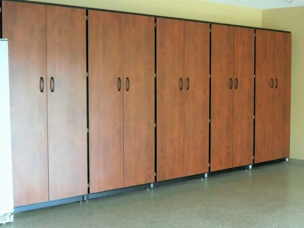 Brown storage cabinets against a yellow wall in a room. Cabinets have black handles and are on rolling bases.