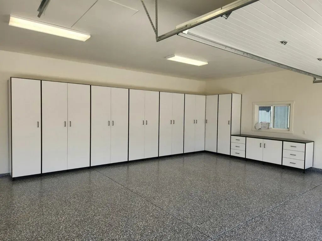 Garage with white storage cabinets and speckled gray flooring.