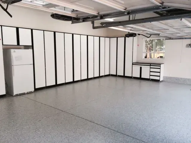 Garage with white cabinets and gray speckled floor.