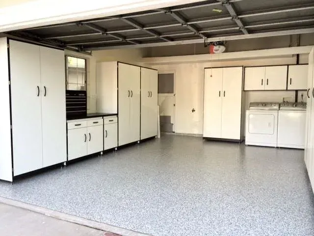 Garage with epoxy floor and white storage cabinets.