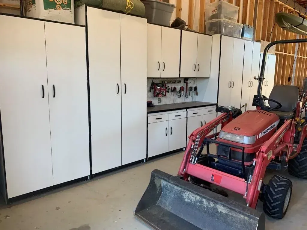 Garage with white storage cabinets and a red tractor.