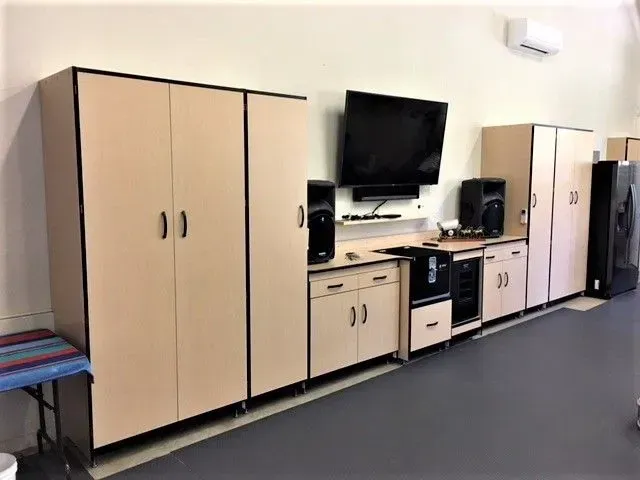 Garage storage cabinets with mounted TV and speakers; neutral tones.