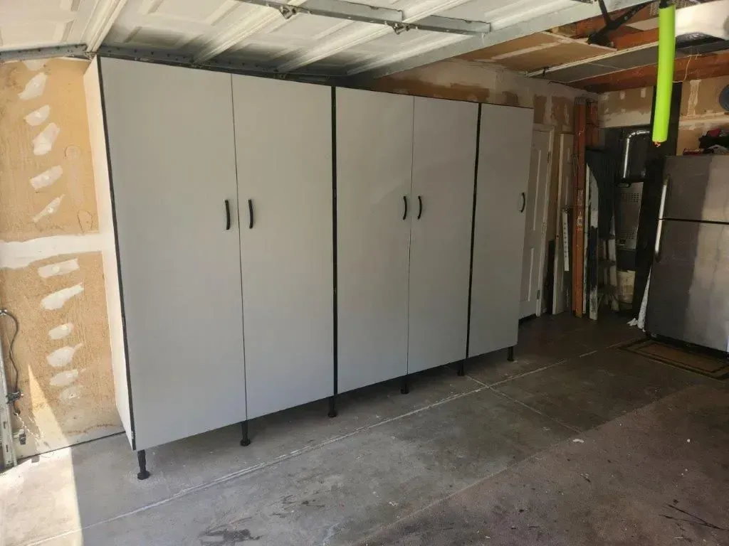 Four tall, gray storage cabinets with black trim and handles, in a garage.