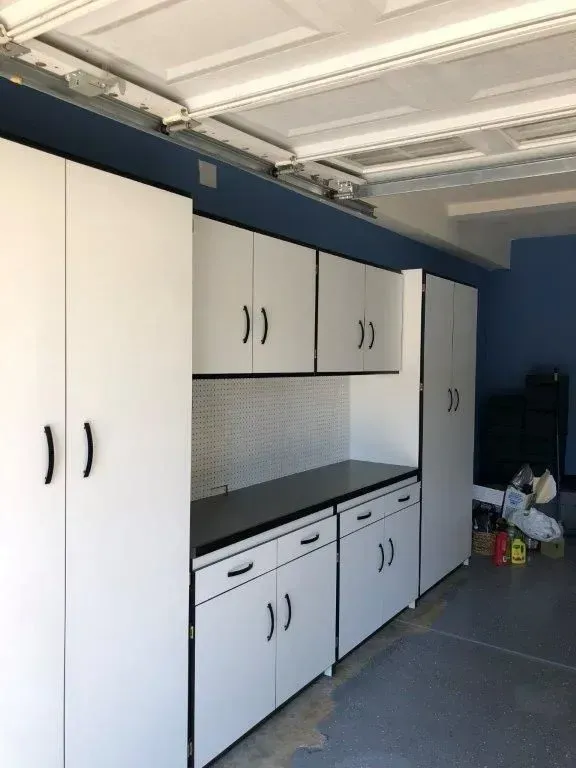White garage storage cabinets with black handles and countertops.