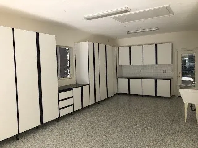 Garage interior with white cabinets, black trim, and speckled gray floor.