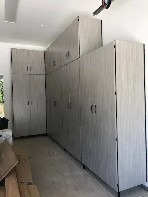Gray storage cabinets installed in a garage, against white walls.