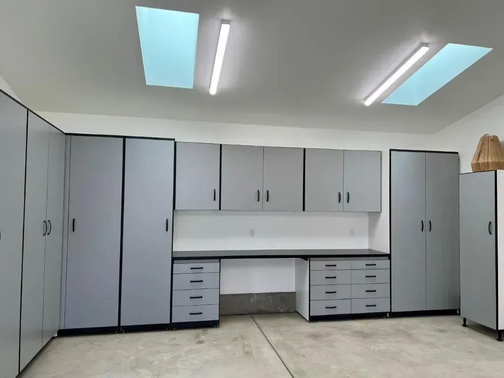 Gray garage cabinets and desk with black trim under skylights.