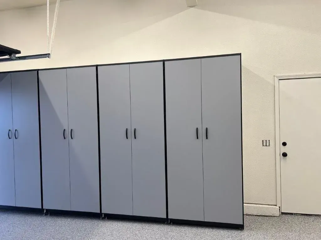 Gray garage storage cabinets and a white door in a garage.