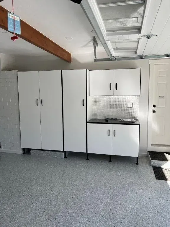 Garage storage cabinets are white with black accents, arranged against a white wall.