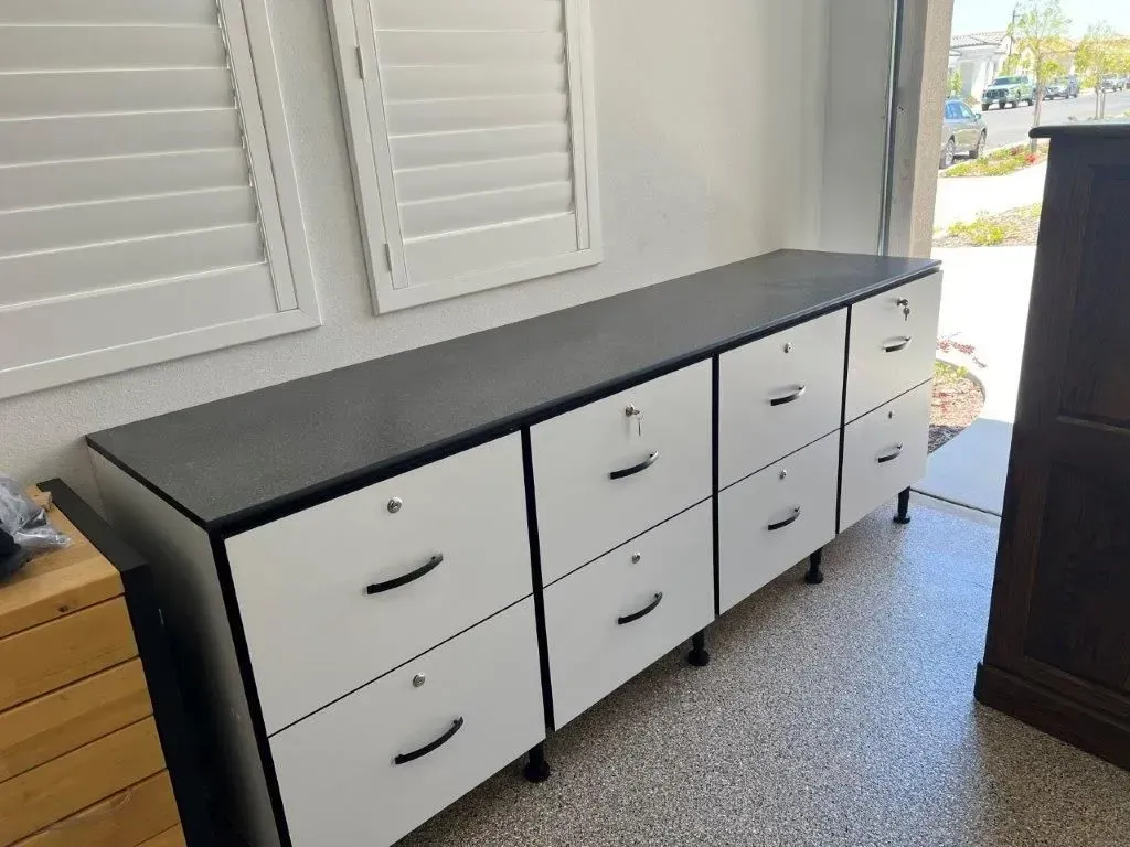 White and black storage cabinet with eight drawers in a garage.