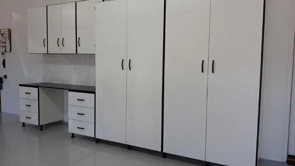 White storage cabinets and desk with black accents in a room.