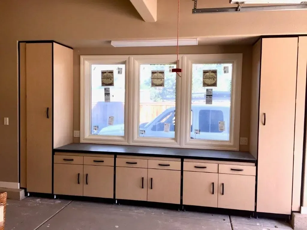 Garage with tan cabinets, a countertop, and a window.