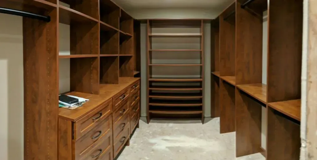 Walk-in closet with dark wood shelving and drawers; carpeted floor.