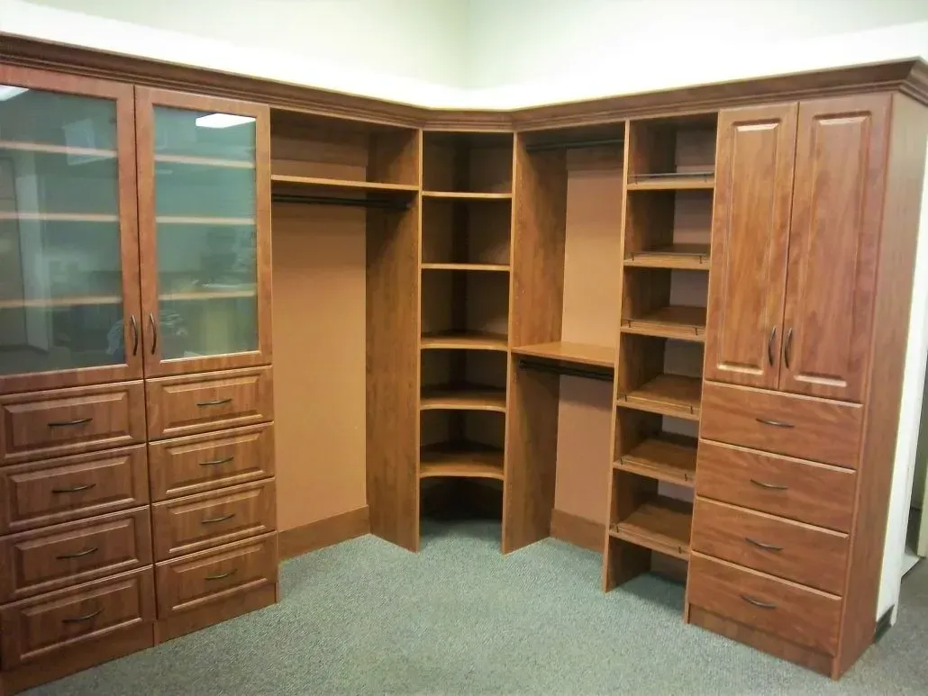 Corner wooden closet with shelving, drawers, and glass-door cabinets, in a room with carpet.