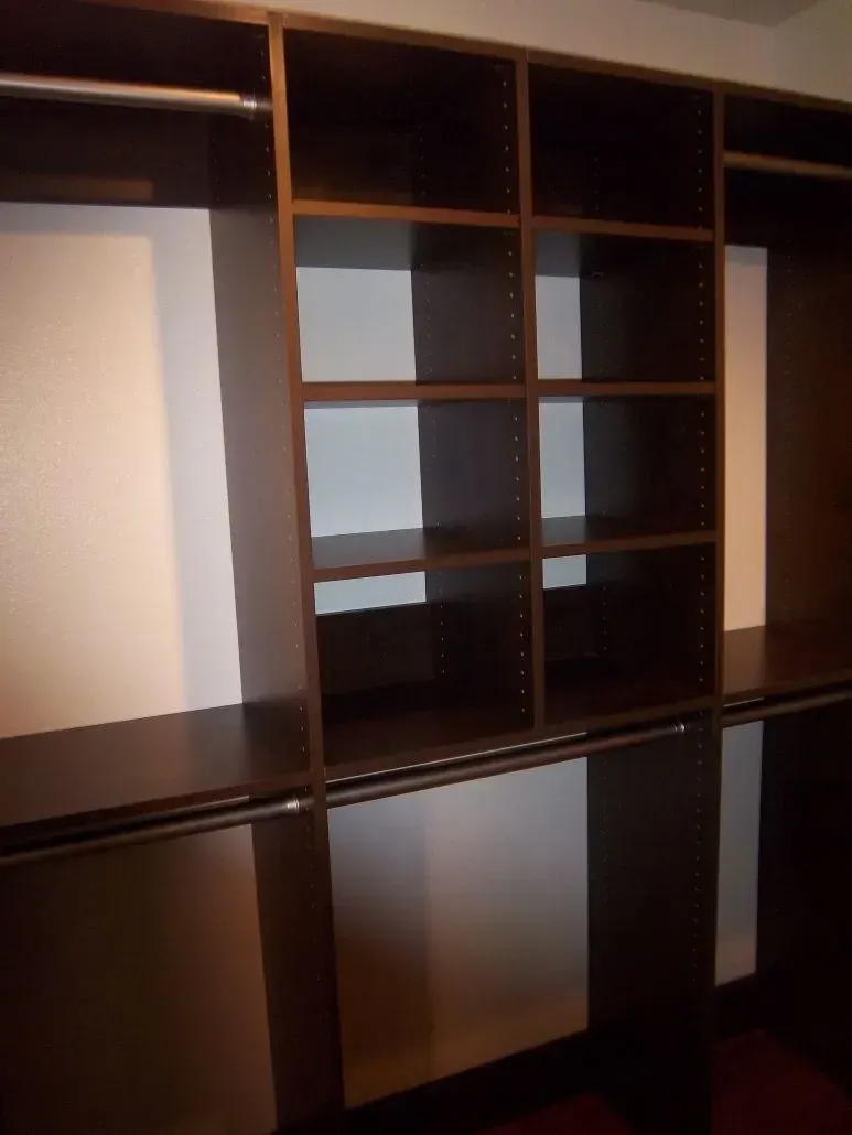 Dark brown closet organizer with shelves, drawers, and hanging rods.