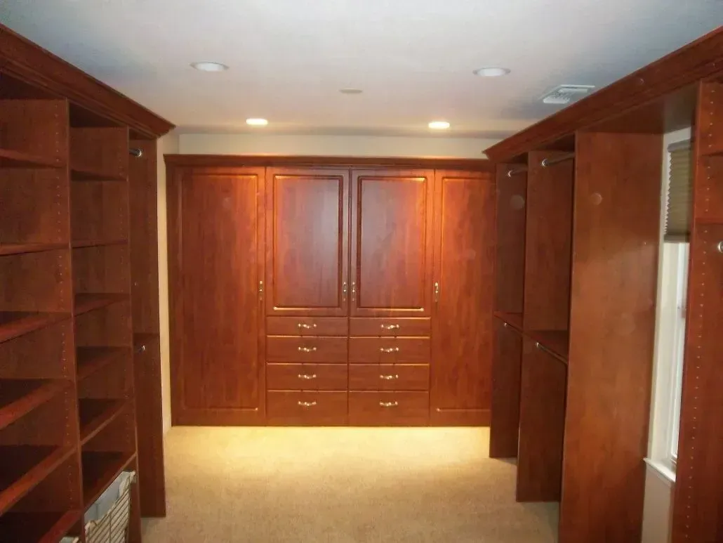 A large, luxurious walk-in closet with dark wood cabinetry and open shelves on either side of the room.