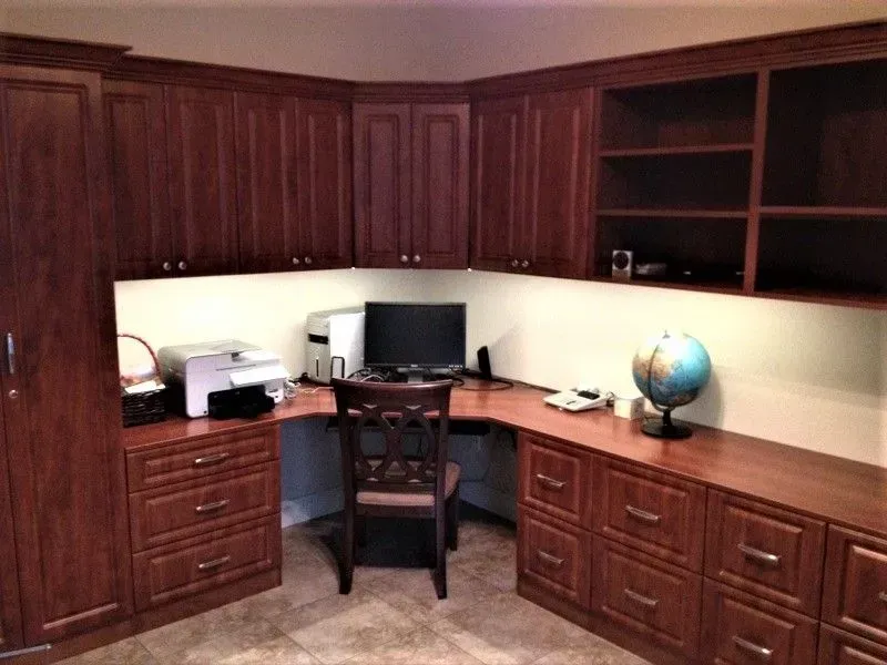 Home office with dark wood cabinets, desk, computer, printer, chair, and globe.