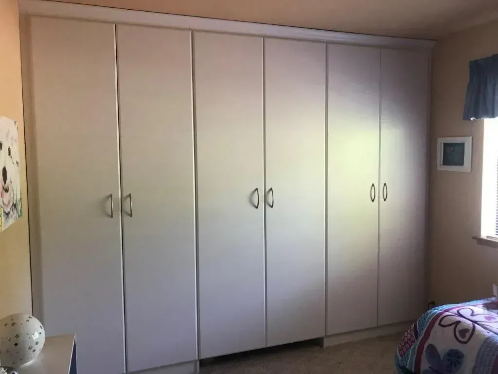 Large white wardrobe against a peach wall in a room.