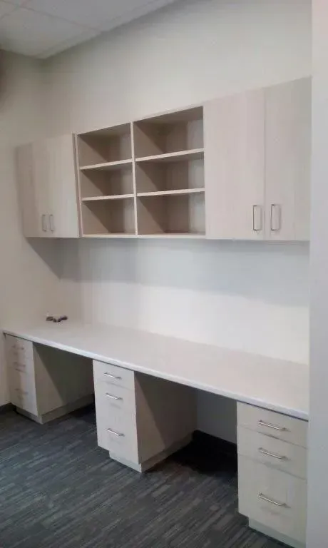 Light-colored office desk and cabinets mounted on a wall. Includes drawers, shelves, and a long countertop.