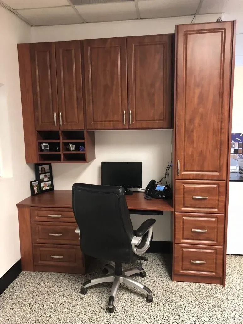 Wooden office desk with storage cabinets and black office chair.